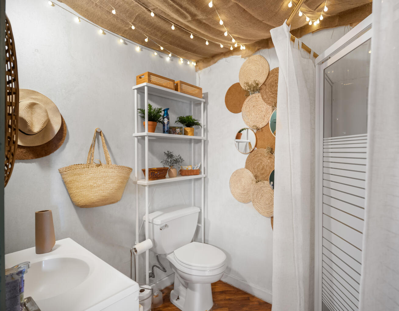 Petite salle de bain blanche avec lavabo, toilette, étagère et douche